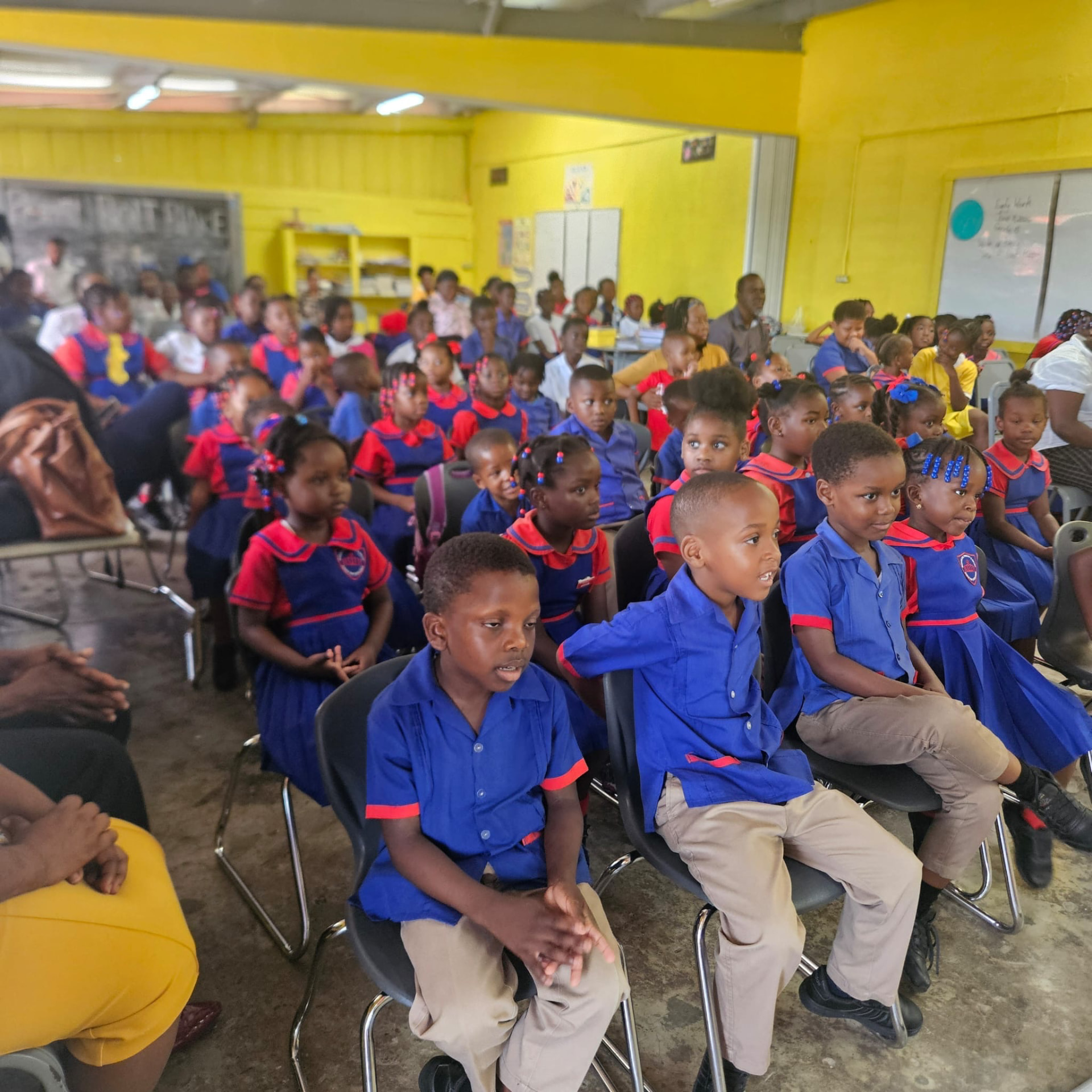 Students in blue and red school uniforms seated together in a yellow classroom at the 2026 Bunkers Hill literacy fair