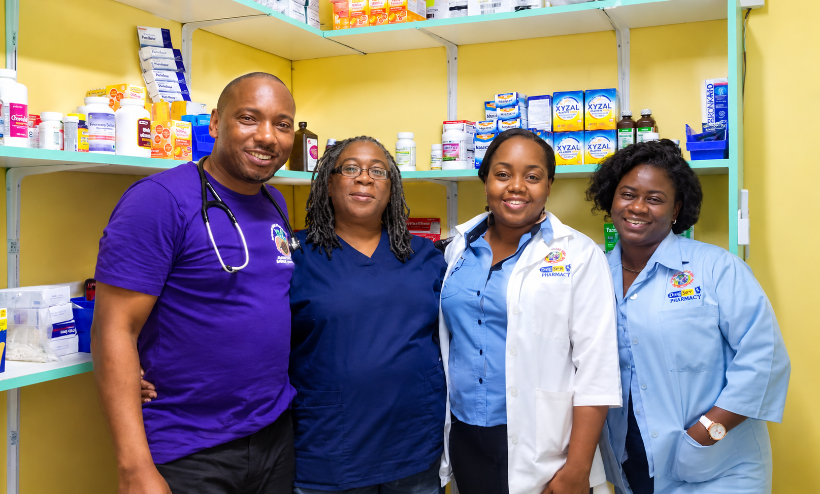 Four health professionals standing side by side inside a pharmacy — a man in a purple shirt with a stethoscope around his neck, a woman in navy scrubs, and two women in light-blue work shirts, one wearing a white lab coat, with shelves of medicines behind them