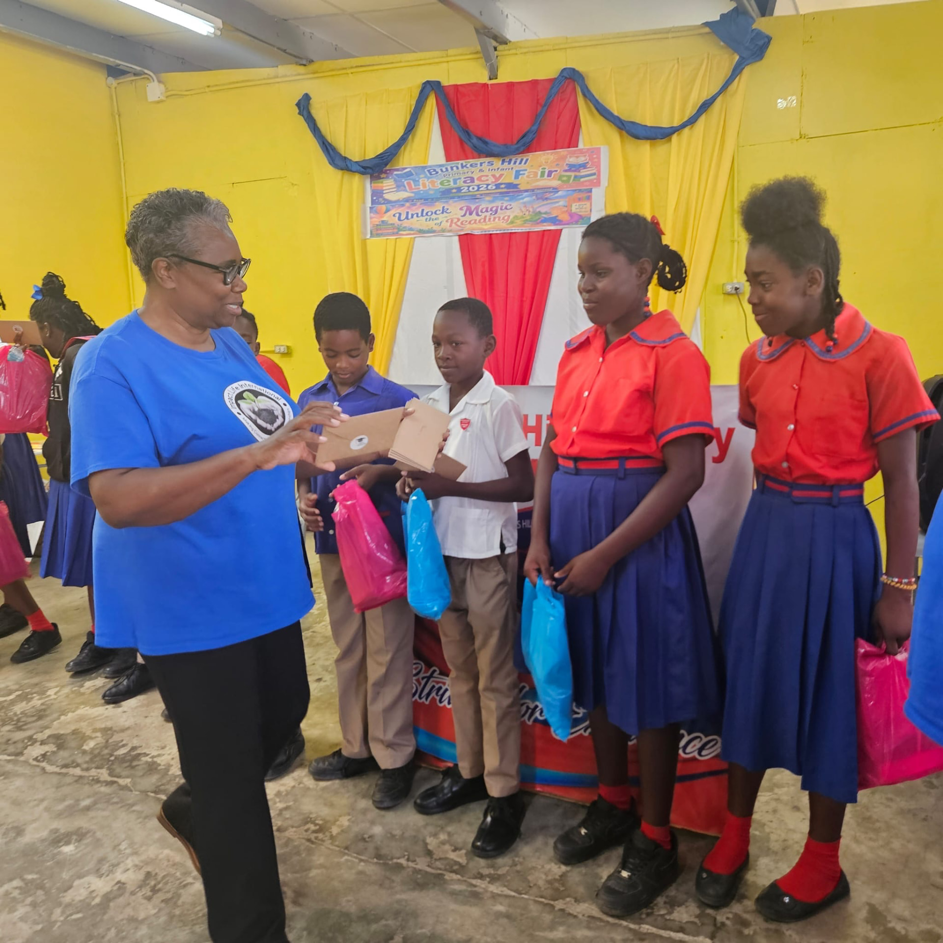 A volunteer with four pupils beneath the Unlock the Magic of Reading literacy fair banner